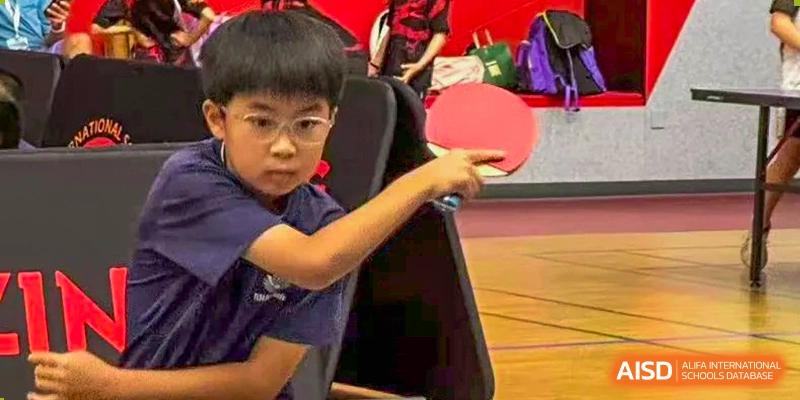 A focused young boy prepares to return a serve during a competitive table tennis game at TEDA International School Tianjin.