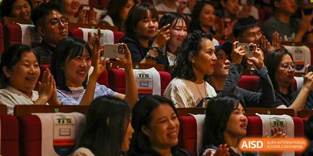 An audience of parents and families watches a student performance with excitement and pride at TEDA International School Tianjin.