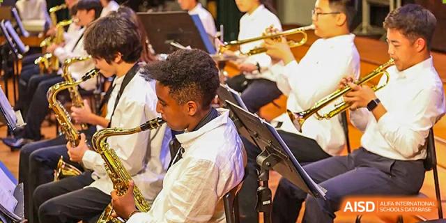 A student musician plays the saxophone during a formal orchestral concert in the school theater at TEDA International School Tianjin.