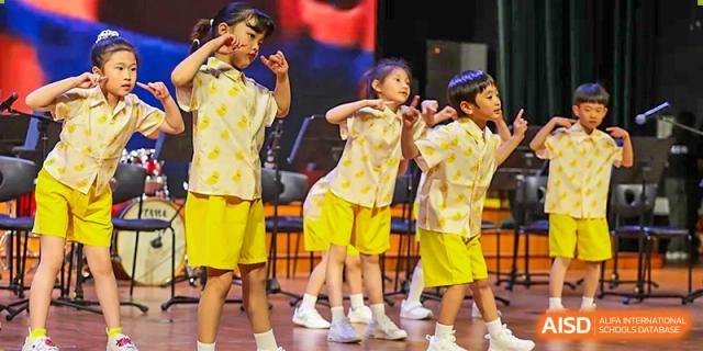 Students in yellow and white uniforms perform a synchronized dance routine for an audience at TEDA International School Tianjin.