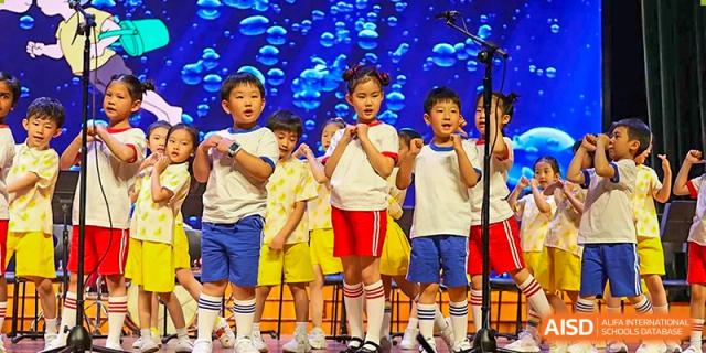 A group of young children in school uniforms sing together during a choral performance at TEDA International School Tianjin.