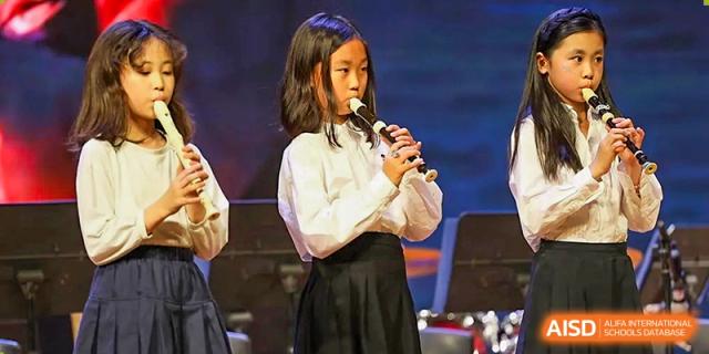 A female student performs a solo on the recorder during a formal music department concert at TEDA International School Tianjin.