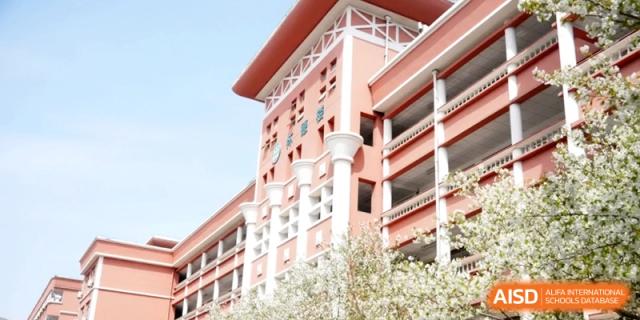 An exterior view of the modern, reddish-orange multi-story building of the educational institution on a sunny day at Ronghaui International School.