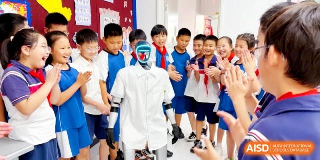 Elementary students excitedly surround a humanoid robot wearing a white shirt in a hallway, interacting with technology at Ronghaui International School.