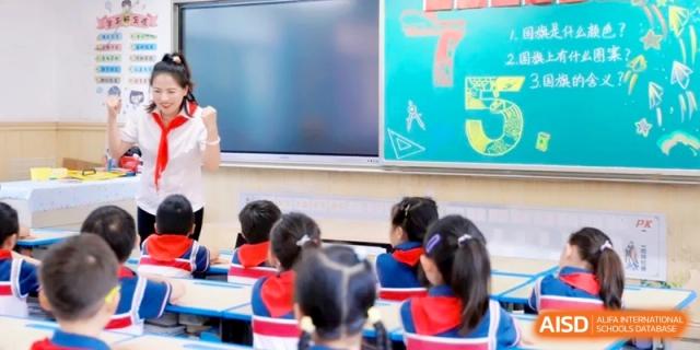 A teacher stands at the front of a colorful classroom next to a digital board, guiding young learners through a math lesson at Ronghaui International School.