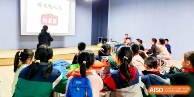 A classroom filled with students listening to a presentation on a large screen, engaged in interactive learning activities at Ronghaui International School.