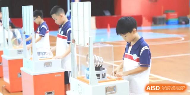 A student carefully examines a robotic arm mechanism placed inside a glass case within a modern technology laboratory at Ronghaui International School.