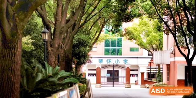The main entrance of a school building surrounded by lush green trees, showcasing a welcoming and peaceful educational environment at Ronghaui International School.