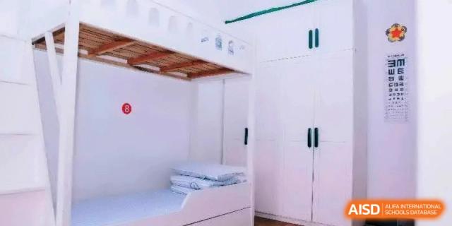 A tidy student dormitory room featuring white bunk beds and built-in wardrobes, providing a comfortable living space at Ronghaui International School.