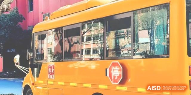 A yellow school bus parked outside, featuring a Chinese stop sign symbol on the side, ready for student transportation at Ronghaui International School.