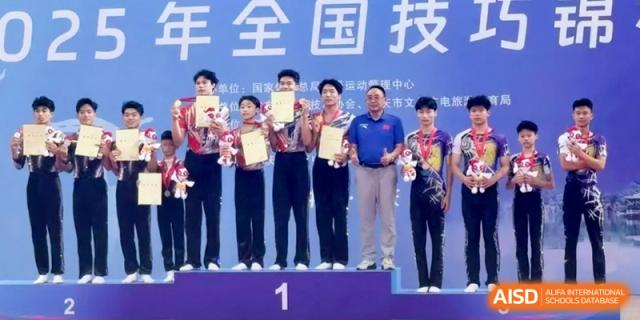 A group of students standing on a podium holding awards and trophies, celebrating their achievement in a national competition at Ronghaui International School.