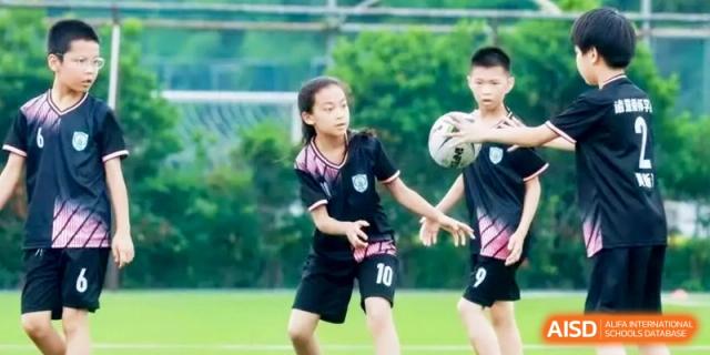 Young soccer players practicing passing and dribbling drills on a lush green outdoor field during a training session at Ronghaui International School.