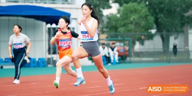 Female athletes sprinting on an outdoor running track during a competitive race, showcasing speed and determination at Ronghaui International School.