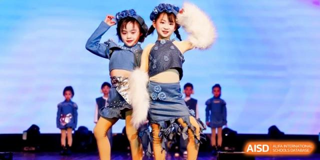 Two young students in denim outfits performing a synchronized dance routine on a brightly lit stage during a school talent showcase at Ronghaui International School.