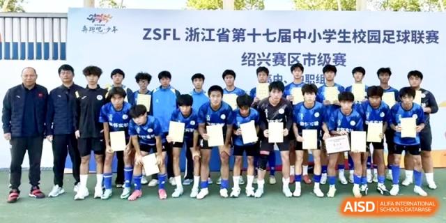 A soccer team posing together for a group photo while holding certificates after a tournament game on a green field at Ronghaui International School.