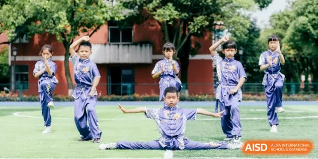 Students performing a martial arts demonstration on a field, showcasing discipline and traditional skills at Ronghaui International School.