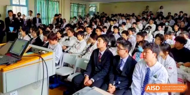 A large group of students in formal school uniforms sit attentively during a lecture at Shanghai Gold Apple Bilingual School.