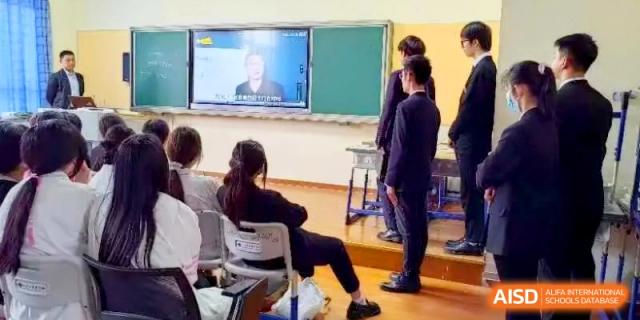 Students stand in a classroom while watching an educational presentation on a large digital screen at Shanghai Gold Apple Bilingual School.
