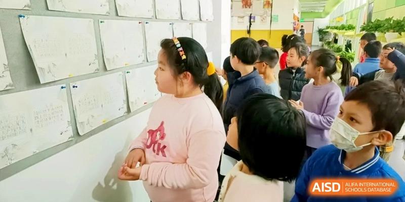 Students gather around a classroom wall to review posted assignments and creative projects at Shanghai Gold Apple Bilingual School.