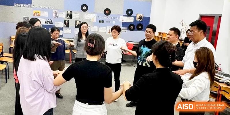 Teachers and staff participate in a collaborative team-building circle in a music room at Shanghai Gold Apple Bilingual School.