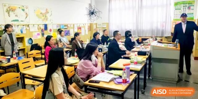 Parents and teachers sit at classroom desks during an evening informational meeting at Shanghai Gold Apple Bilingual School.