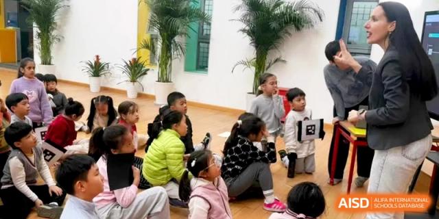 A group of students watches a presentation while sitting together in a bright, modern classroom at Shanghai Gold Apple Bilingual School.