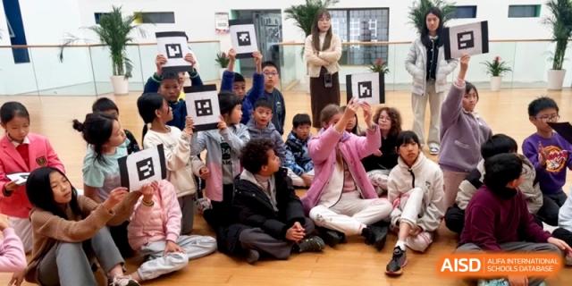 Students sit on the floor holding up QR code cards for an interactive classroom activity at Shanghai Gold Apple Bilingual School.
