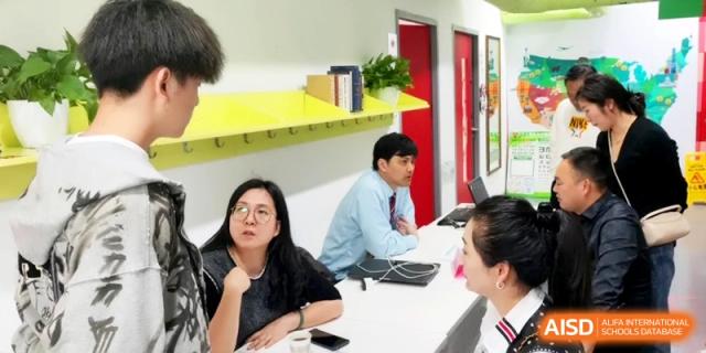 Teachers and staff engage in a collaborative meeting in a colorful, well-lit office area at Shanghai Gold Apple Bilingual School.