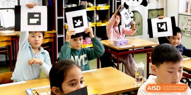 Students in a classroom hold up black and white AR marker cards during an interactive lesson at Shanghai Gold Apple Bilingual School.
