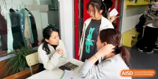 A student speaks with two faculty members during a one-on-one progress discussion at Shanghai Gold Apple Bilingual School.