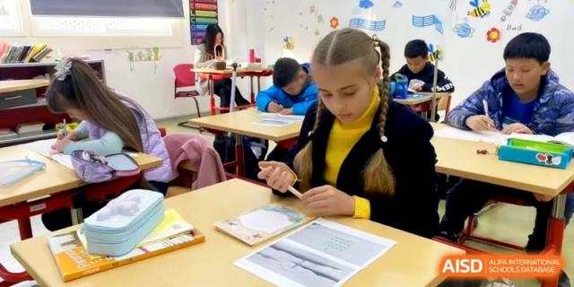 A student with braided hair works diligently on a creative project at her classroom desk at Shanghai Gold Apple Bilingual School.