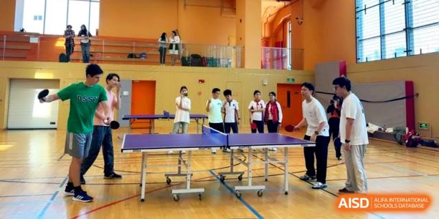 Students engaged in a competitive table tennis match in the indoor sports hall at Shanghai Gold Apple Bilingual School.