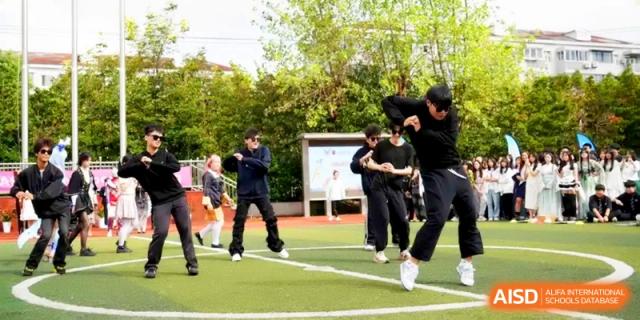 Students dressed in black street-style outfits performing a modern dance routine outdoors at Shanghai Gold Apple Bilingual School.
