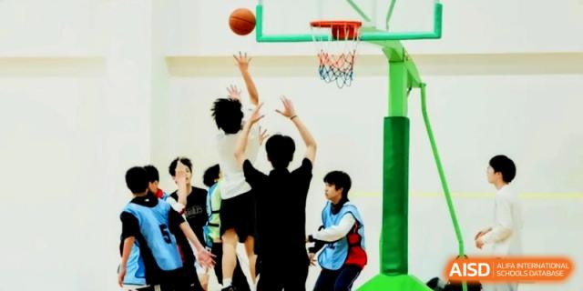 A student jumps to take a shot at a basketball hoop during an indoor game at Shanghai Gold Apple Bilingual School.