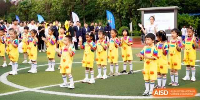Young children in yellow uniforms perform a coordinated routine on the outdoor track at Shanghai Gold Apple Bilingual School.
