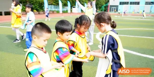 Young students in bright yellow vests participate in a group activity on the green field at Shanghai Gold Apple Bilingual School.