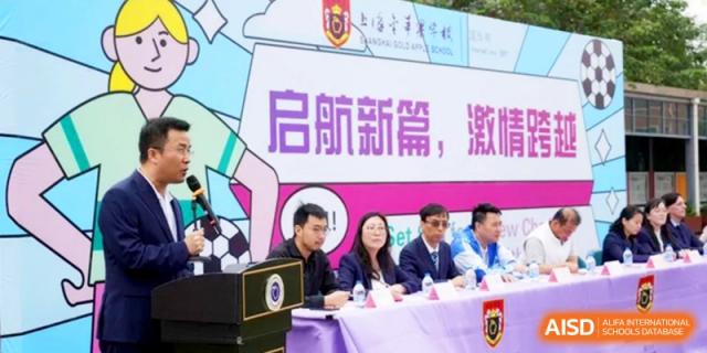School officials and guests sit at a formal table during a presentation or ceremony at Shanghai Gold Apple Bilingual School.