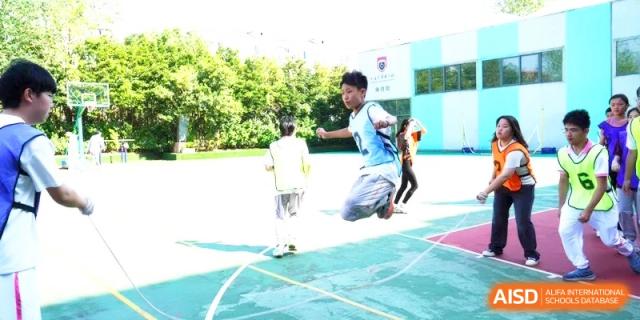 A student athlete performs a high jump on an outdoor court at Shanghai Gold Apple Bilingual School.