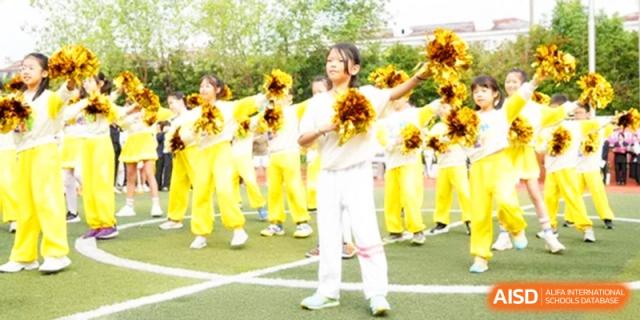 The cheerleading squad performs a routine with yellow pom-poms at Shanghai Gold Apple Bilingual School.