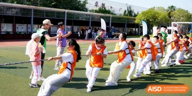 Students participate in a spirited tug-of-war competition outdoors at Shanghai Gold Apple Bilingual School.