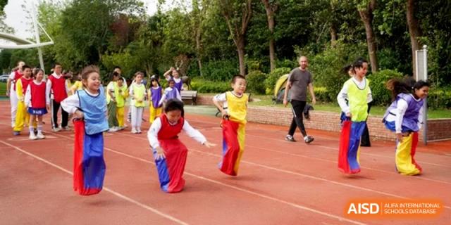 Children participate in a fun sack race on the red running track at Shanghai Gold Apple Bilingual School.