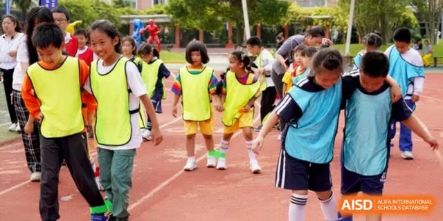 Young students in colorful jerseys gather for a sports activity at Shanghai Gold Apple Bilingual School.