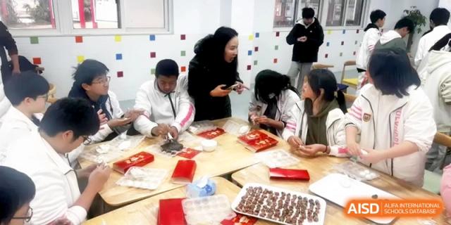 A group of students and a teacher work together around a table to prepare traditional food at Shanghai Gold Apple Bilingual School.
