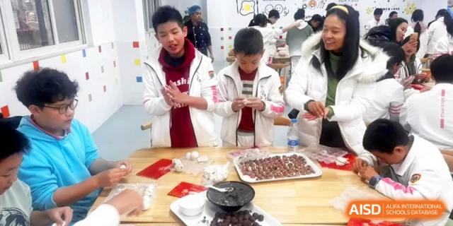 Students in white uniforms carefully roll dough for a cultural cooking activity at Shanghai Gold Apple Bilingual School.