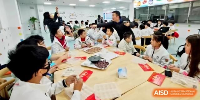 A large group of students gathers around classroom tables to celebrate a cultural festival at Shanghai Gold Apple Bilingual School.