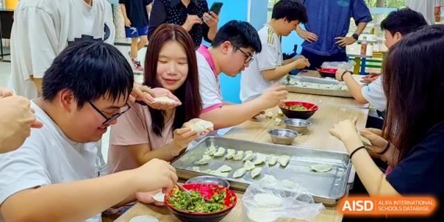 A group of teenagers works together to hand-craft dumplings, placing them neatly on metal trays at Shanghai Gold Apple Bilingual School.