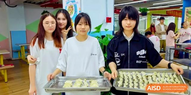 Three students stand proudly holding large trays filled with rows of freshly made dumplings at Shanghai Gold Apple Bilingual School.