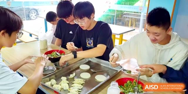 Boys in a dining hall carefully assemble dumplings, using round dough skins and vegetable filling at Shanghai Gold Apple Bilingual School.