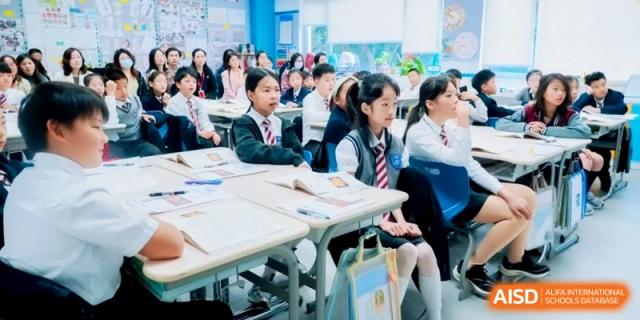 Students in school uniforms sit at their desks with open books, listening to a lecture in a bright room at Shanghai Qingpu World Foreign Language High School.