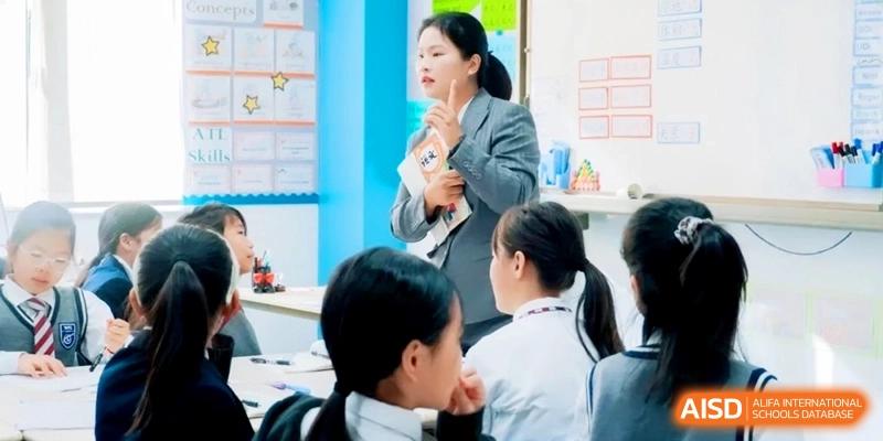 A teacher holds a book and gestures with one finger during a lesson as students look on attentively at Shanghai Qingpu World Foreign Language High School.